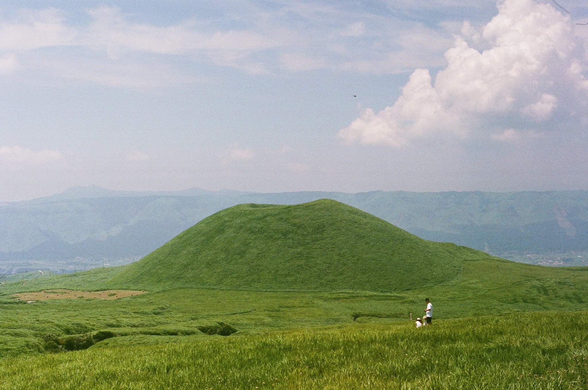 米塚と草原を歩く人々