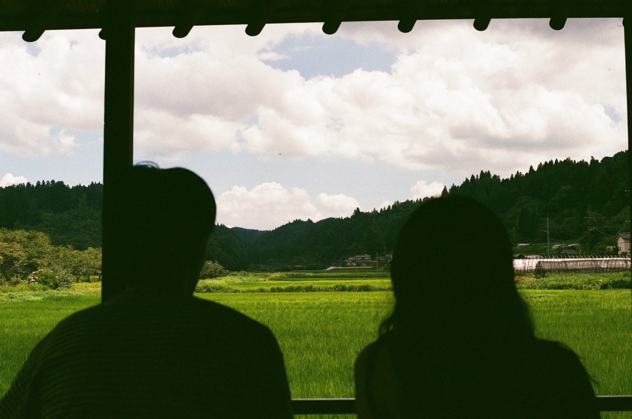 縁側から眺める水田と山の風景、シルエットの二人