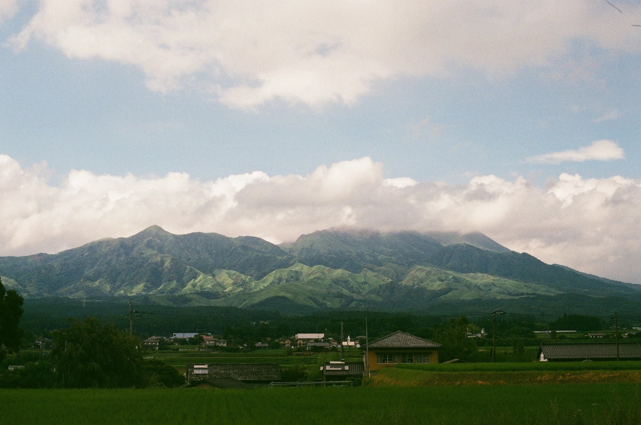 夕方の光に照らされる阿蘇の山並みと集落