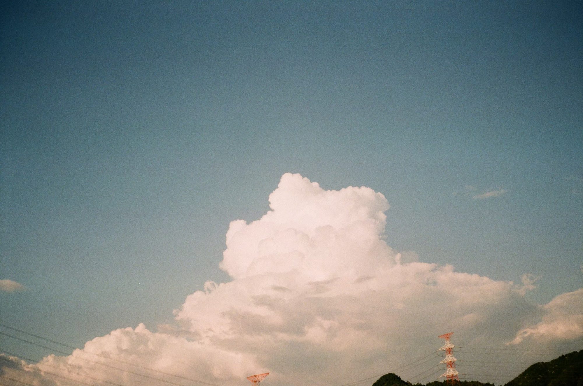 送電線の鉄塔の上に広がる大きな入道雲