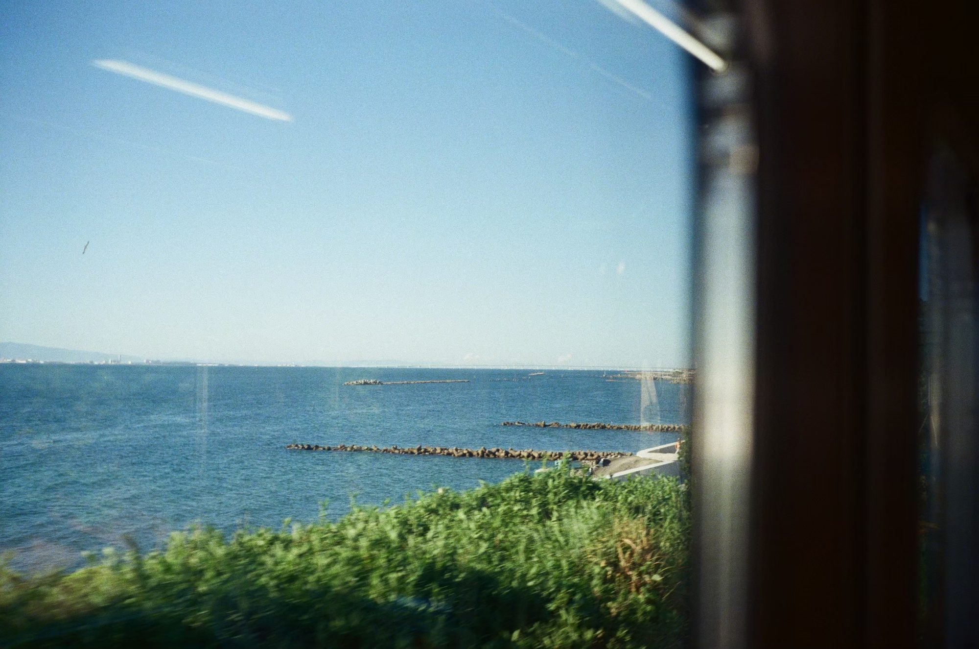 電車の車窓から見える青い海と空