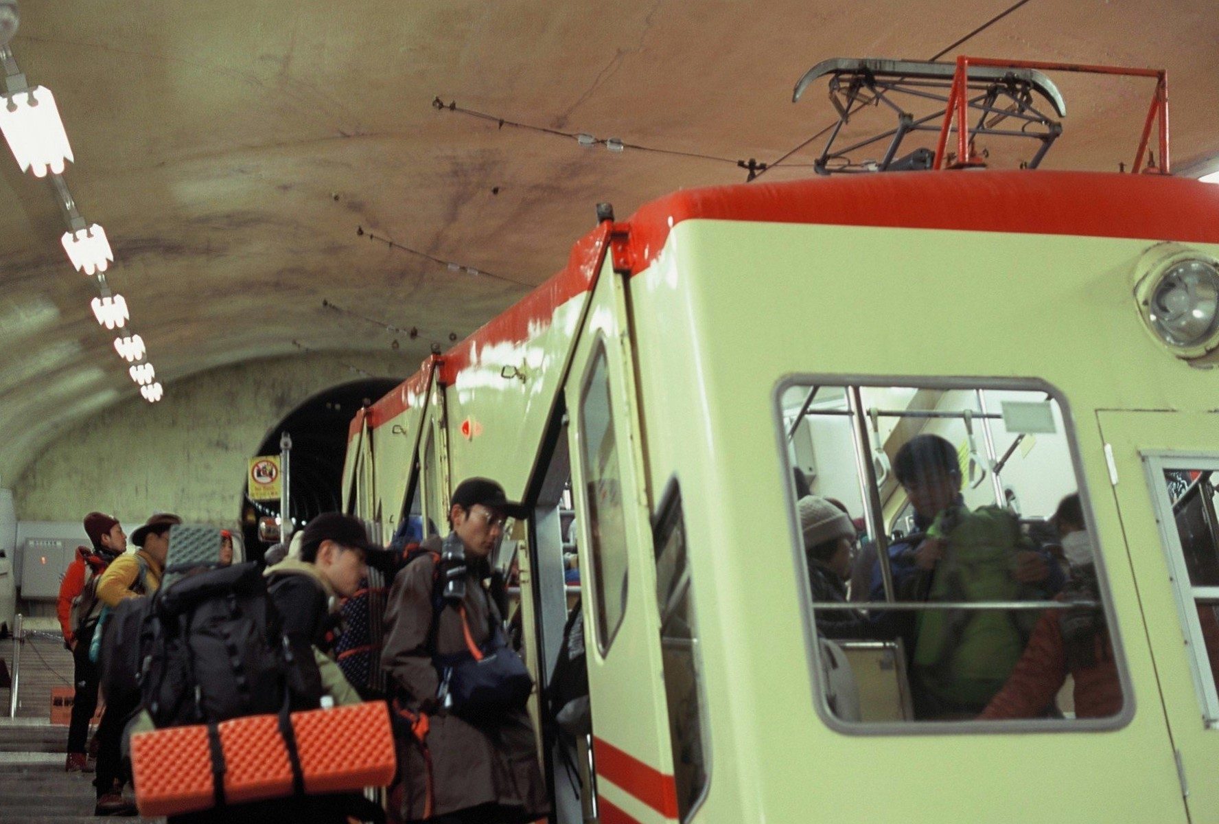 トンネル駅のケーブルカーに乗り込む登山客たち